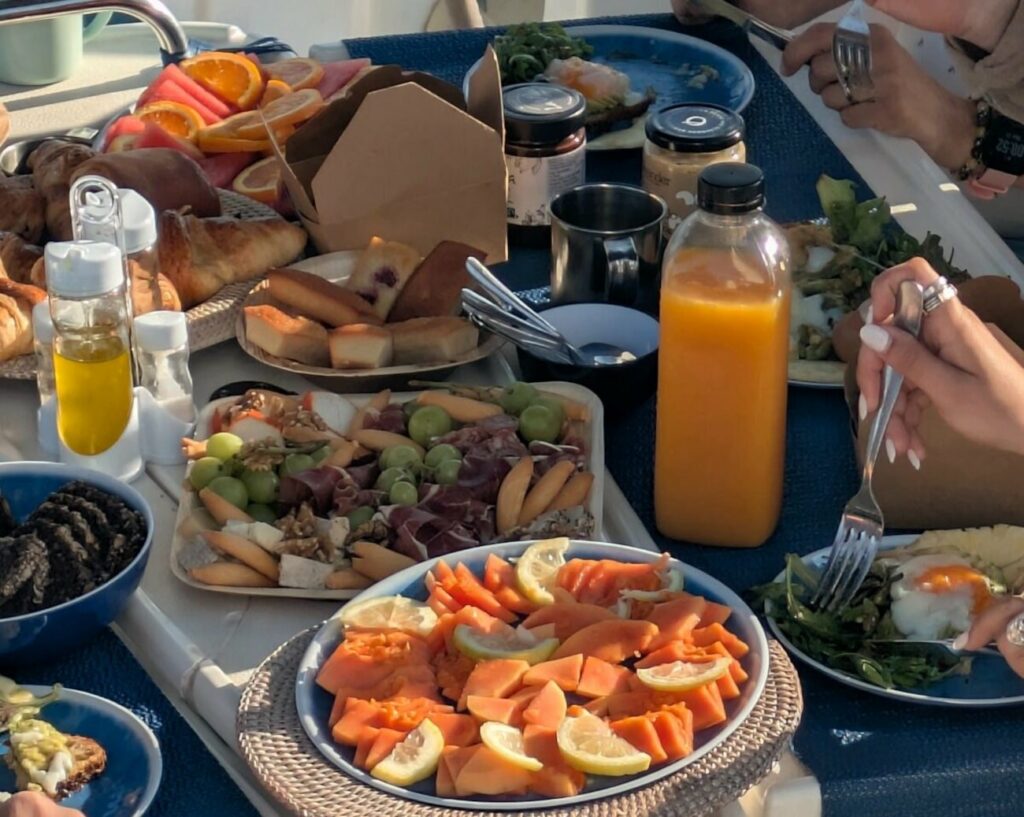 Charter Catering Poca Pots — brunch dressé à bord, papaye fraîche et plateau charcuterie
