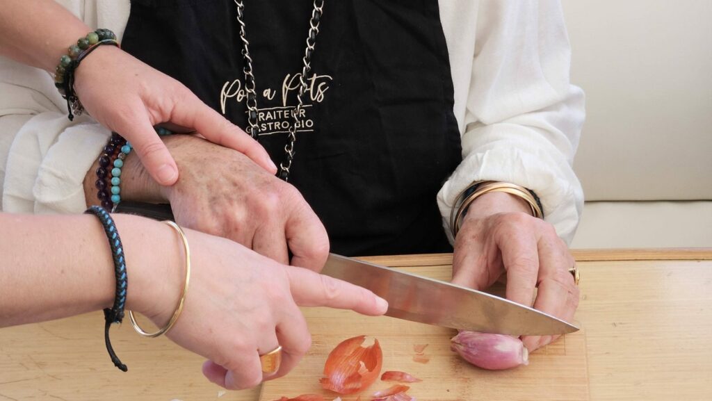 La cheffe guide la découpe au couteau, tablier Poc a Pots