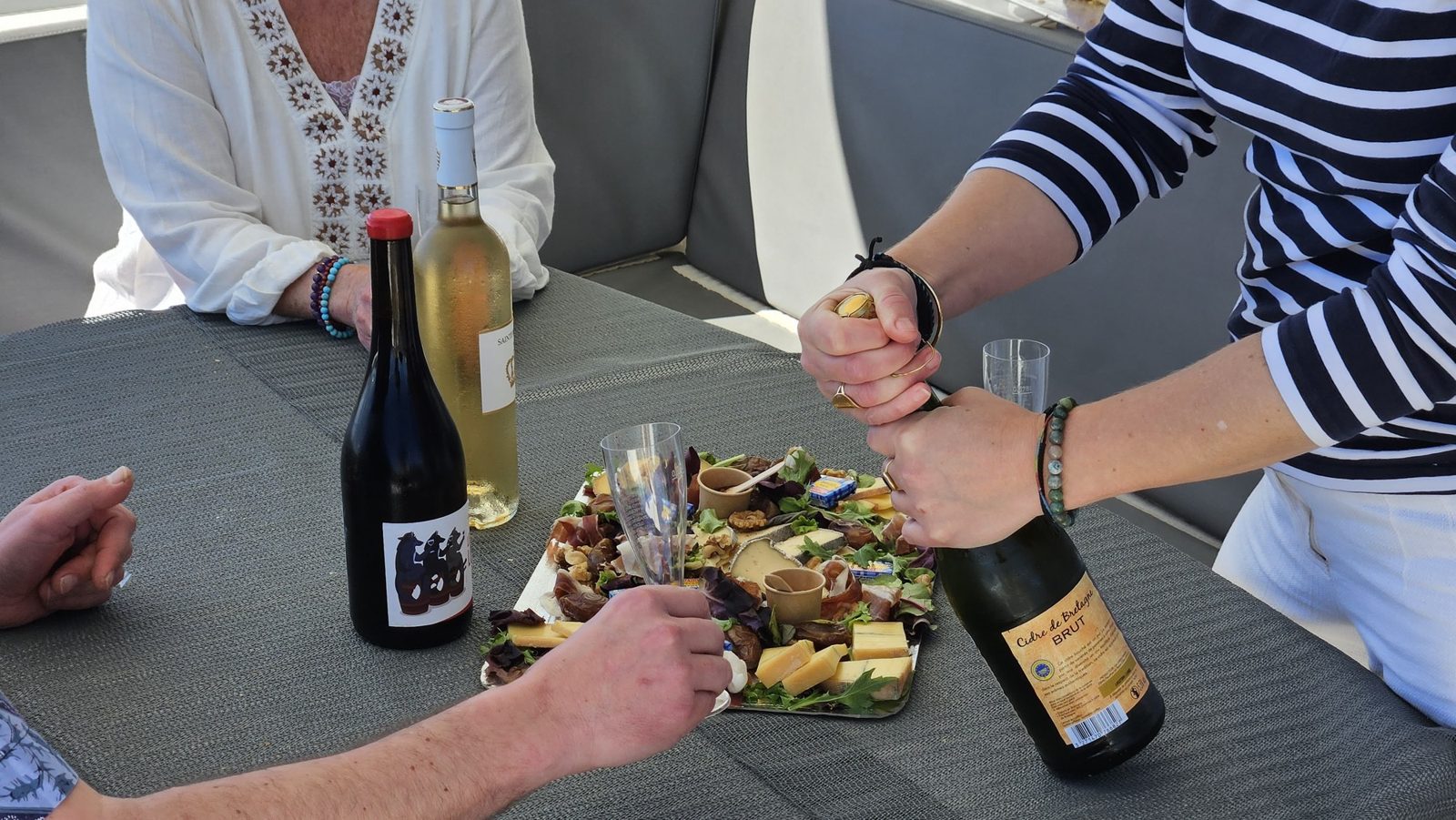 Service des vins naturels autour d'une planche charcuterie-fromage à bord