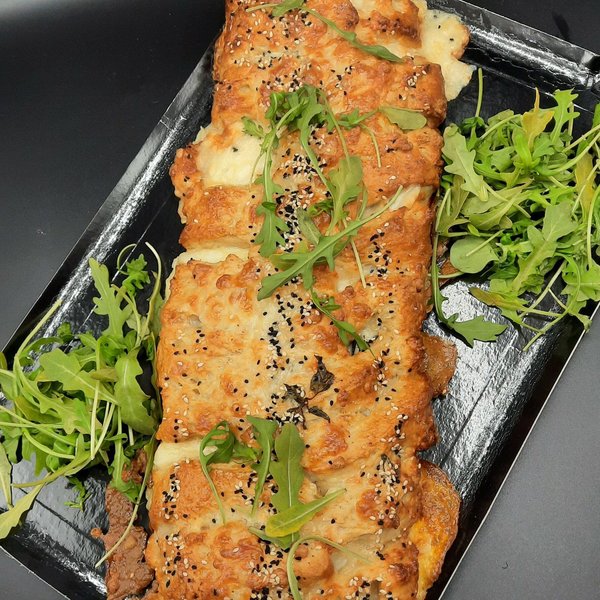 Brioche salée tranchée sur plaque, servie avec de la roquette