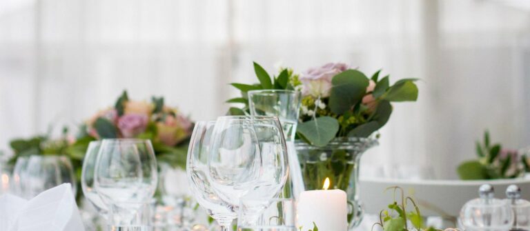 Taula parada per a una recepció: copes de vi, espelmes i composicions florals