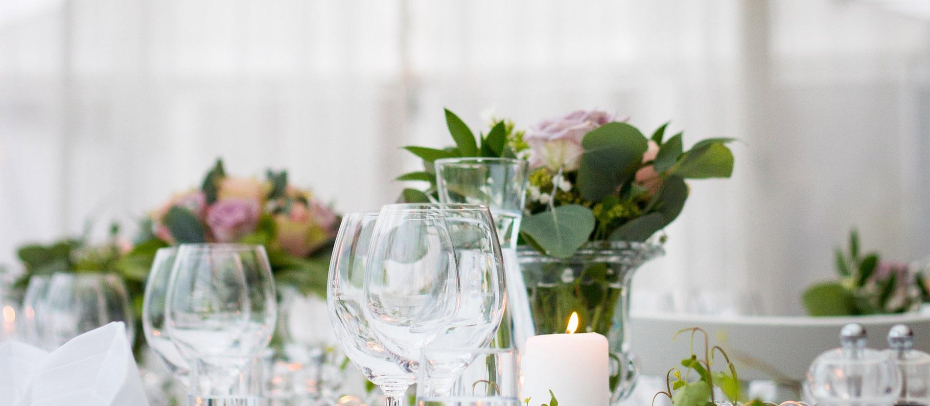 Table dressée pour une réception : verres à vin, bougies et compositions florales