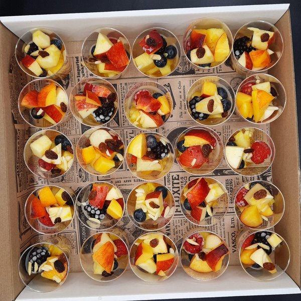 Verrines de salade de fruits frais alignées dans une boîte de livraison traiteur